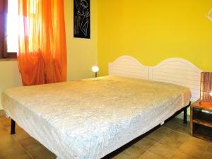 a bedroom with a white bed in a yellow wall at Holiday Home Rei Mare Fronte Marina - REI205 by Interhome in Monte Nai