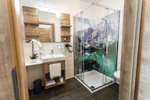 uma casa de banho com uma cabina de duche em vidro e um lavatório. em Dachsteinresort em Russbach am Pass Gschütt