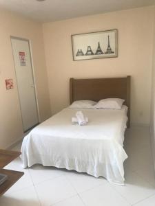 a bedroom with a white bed with a towel on it at Hotel Pousada Irmaos Freyhardt in Rio de Janeiro