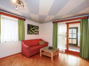 a living room with a red couch and a table at Apartment Schwarzwald 6 EG by Interhome in Radenthein