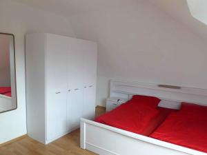 a white bedroom with a red bed and white cabinets at Holiday Home Adda by Interhome in Neßmersiel