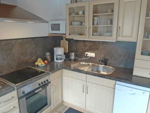 a kitchen with white cabinets and a sink at Holiday Home Adda by Interhome in Neßmersiel