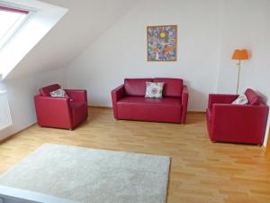 a living room with two red chairs and a rug at Holiday Home Adda by Interhome in Neßmersiel