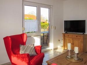 uma sala de estar com uma cadeira vermelha e uma televisão em Holiday Home Entenkoje by Interhome em Dornum