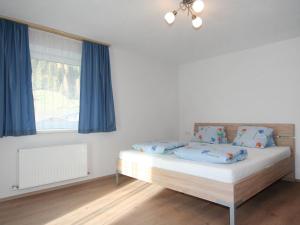 a bedroom with a bed with blue curtains and a window at Apartment Alpenrose-2 by Interhome in See