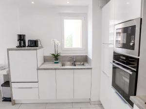 uma cozinha branca com um lavatório e um micro-ondas em Apartment Le Méditerranée-2 by Interhome em Fréjus