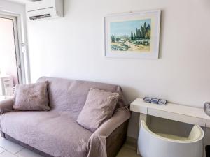 um sofá numa sala de estar com uma fotografia na parede em Apartment Le Méditerranée-2 by Interhome em Fréjus