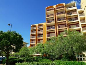 un edificio de apartamentos amarillo con árboles delante de él en Studio Le Capitole-6 by Interhome en Fréjus