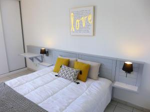 uma cama com almofadas amarelas e brancas em Apartment L'Open-6 by Interhome em Fréjus