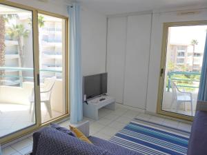 sala de estar con sofá azul y TV en Apartment L'Open-6 by Interhome, en Fréjus