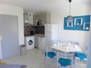 a kitchen with a white table and blue chairs at Apartment L'Open-6 by Interhome in Fréjus +15 photos