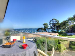 een tafel met een dienblad met eten op een balkon met uitzicht op de oceaan bij Apartment Le Parc de La Ronceray-1 by Interhome in Dinard