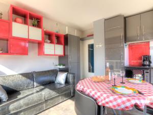een keuken met een tafel, een bank en rode keukenkastjes bij Apartment Le Parc de La Ronceray-1 by Interhome in Dinard
