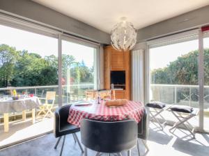 een eetkamer met een tafel, stoelen en ramen bij Apartment Le Parc de La Ronceray-1 by Interhome in Dinard