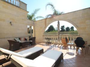 un patio avec des chaises et des tables ainsi qu'un mur en briques dans l'établissement Villa Alberto by Interhome, à Marina di Lizzano