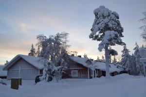 a barn covered in snow next to a tree at Saaritupa Apartment Saariselkä in Saariselka