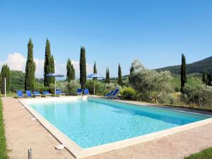 a swimming pool with chairs and umbrellas and trees at Apartment Le Sodole - Petunia by Interhome in San Gimignano