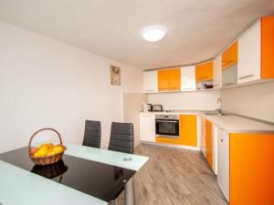 una cucina con armadi arancioni e bianchi e un tavolo di Holiday Home Snježana by Interhome a Ražanj