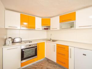 una cucina con elettrodomestici e armadi bianchi e arancioni di Holiday Home Snježana by Interhome a Ražanj