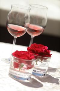 ライト・イム・ヴィンクルにあるBeim Rottmeisterのワイン2杯と赤いバラのテーブル
