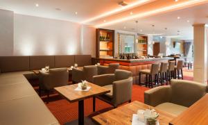 a restaurant with tables and chairs and a bar at Morada Hotel Heidesee Gifhorn in Gifhorn