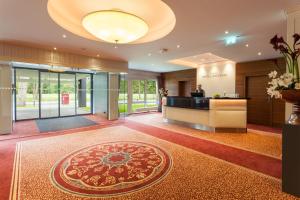 a lobby with a reception desk and a rug at Morada Hotel Heidesee Gifhorn in Gifhorn