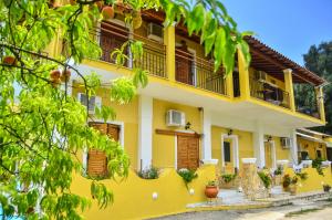 een geel huis met balkons en planten bij Kapases Studios & Apartments in Peroulades
