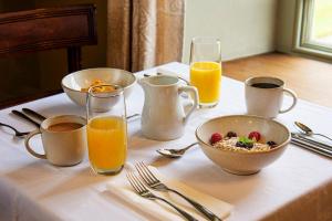 une table avec un bol de céréales et des verres de jus d'orange dans l'établissement Cusgarne Manor boutique B&B - adults only, à Cusgarne 33 autres photos