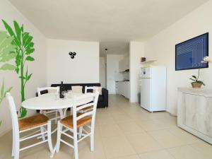 una cucina e una sala da pranzo con tavolo e sedie bianchi di Apartment Vista Playa 2 by Interhome a Pittulongu