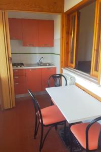 een keuken met rode kasten en een witte tafel en stoelen bij Apartment Costa di Kair ed Din-7 by Interhome in Sperlonga