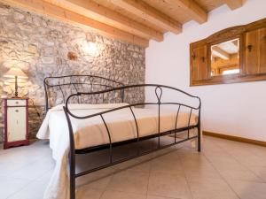 a bedroom with a metal bed in a stone wall at Apartment Albergo Diffuso - Cjasa Ustin-4 by Interhome in Barcis