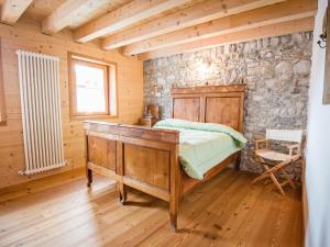a bedroom with a bed and a stone wall at Apartment Albergo Diffuso - Cjasa Ustin-5 by Interhome in Barcis