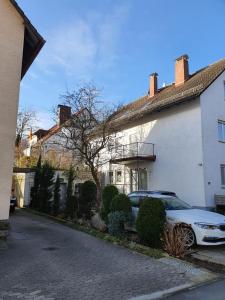a car parked in front of a white house at Luxus Ferienwohnung in Pfungstadt