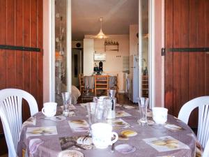 - une table avec des chaises blanches et un chiffon de table dans l'établissement Apartment Le Méditerranée-2 by Interhome, au Barcarès