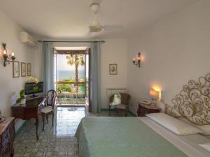 sypialnia z łóżkiem, biurkiem i oknem w obiekcie Semiramis Hotel De Charme & Pools w mieście Ischia