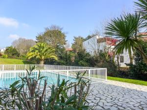 een zwembad met een wit hek naast een huis bij Apartment Le clos Xapella by Interhome in Bidart