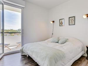 een witte slaapkamer met een bed en een groot raam bij Apartment Le clos Xapella by Interhome in Bidart