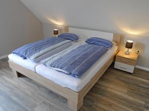 ein Schlafzimmer mit einem großen Bett mit blauer Bettwäsche und blauen Kissen in der Unterkunft Apartment Alina by Interhome in Marienhafe + 16 Fotos