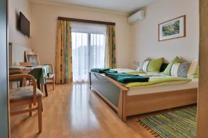 Un dormitorio con una cama y una mesa y una ventana. en Gasthof Bader, en Deutsch Goritz