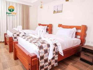 um quarto com 2 camas e lençóis brancos em Pori City Hotel em Nairobi