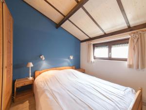 デ・ハーンにあるHoliday Home Polderhuis nr-142 by Interhomeの青い壁と窓のあるベッドのある寝室