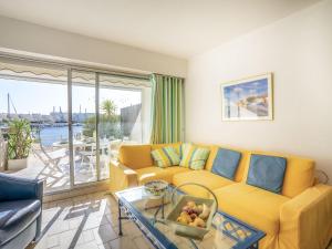 a living room with a yellow couch and a glass table at Holiday Home Hélios by Interhome in Le Grau-du-Roi