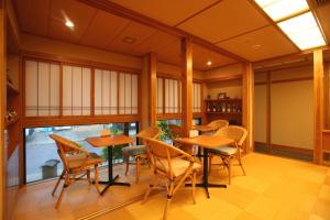 a dining room with tables and chairs and a large window at Kutsurogi no yado Kiunsoh in Oda