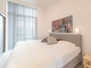 a bedroom with a white bed and a painting on the wall at Holiday Home Ruisweg 59 by Interhome in Wemeldinge