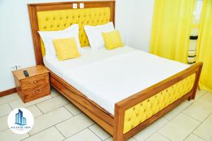 una camera con un grande letto con testiera gialla di Atlantic View Apartments a Limbe