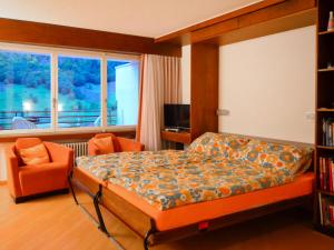 ein Schlafzimmer mit einem Bett, einem Stuhl und einem Fenster in der Unterkunft Apartment Ringstrasse - Utoring-24 by Interhome in Leukerbad