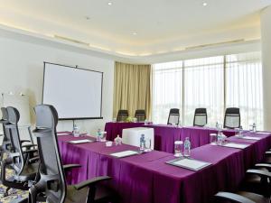 una sala conferenze con tavoli e sedie viola e schermo di Sensa Hotel Bandung a Bandung