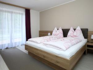 sypialnia z łóżkiem z białą pościelą i różowymi poduszkami w obiekcie Apartment Schwarzwald 6 OG by Interhome w mieście Radenthein