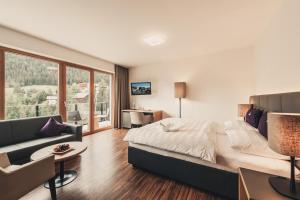 een slaapkamer met een bed, een bank en een bureau bij ALFA hotel in Serfaus