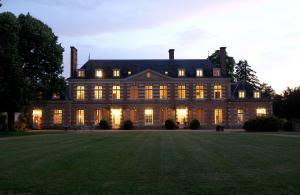 ein großes Haus mit nachts eingeschaltetem Licht in der Unterkunft Château de la Giraudière in Villeny